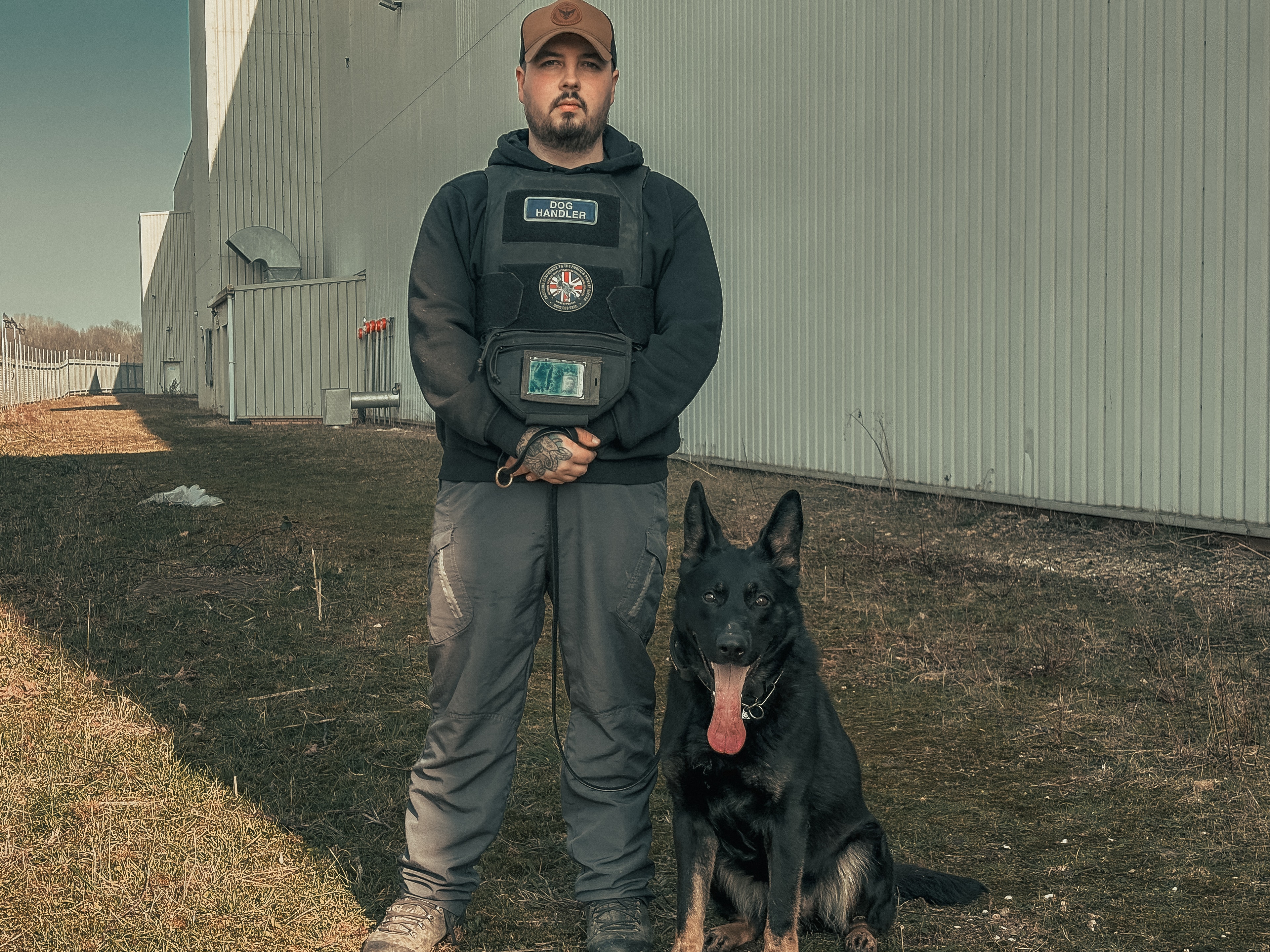Dog handler standing with a working K9 outside an operational site