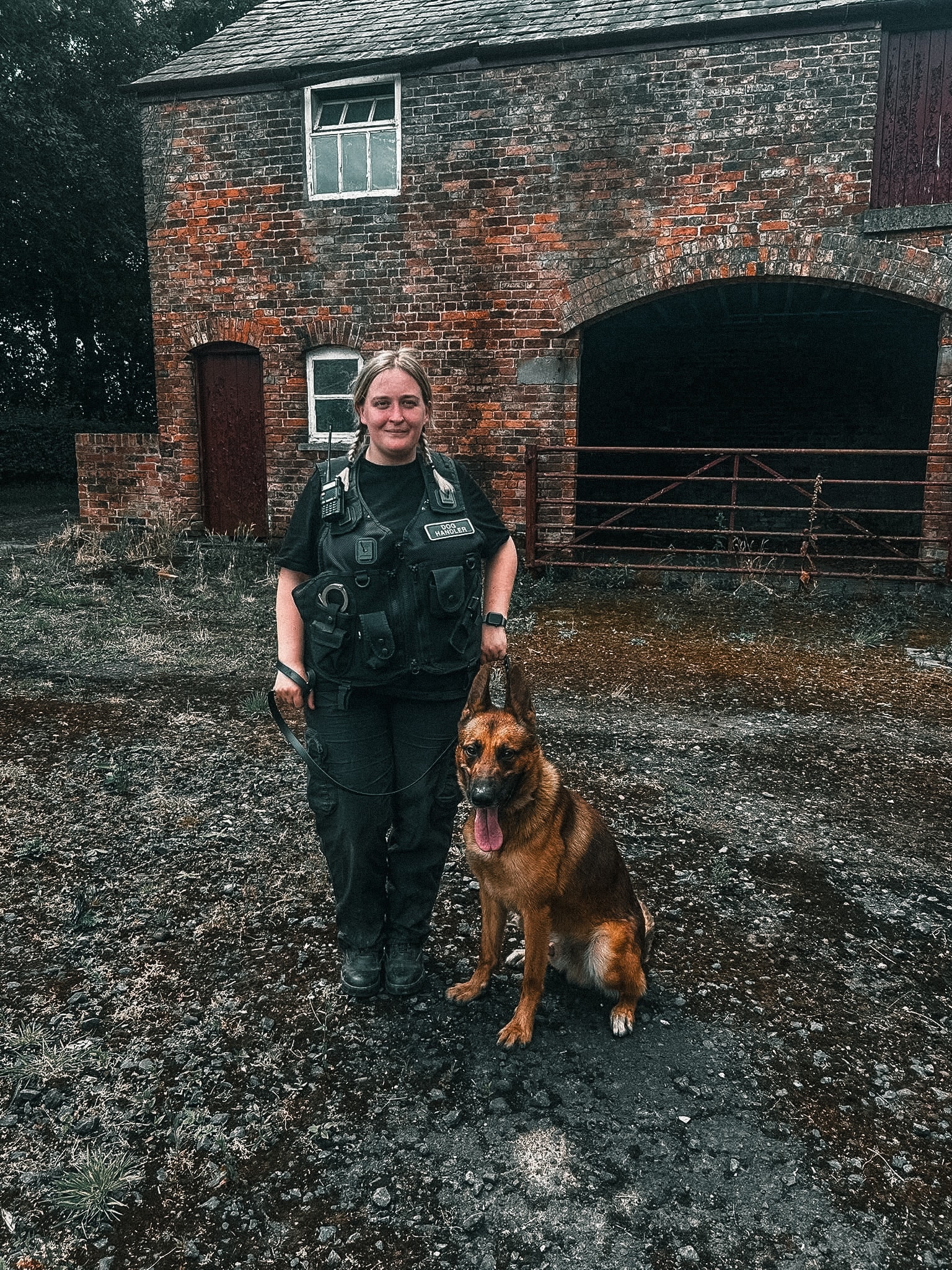 Dog handler with a working K9 outside a brick building